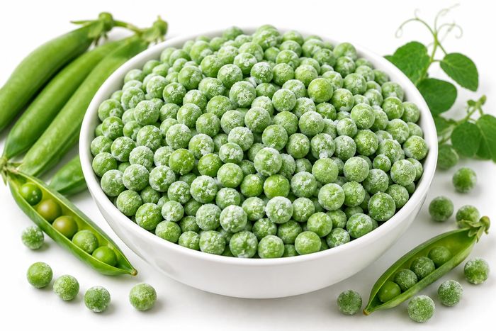 Frozen green peas in a bowl with fresh pods beside them.