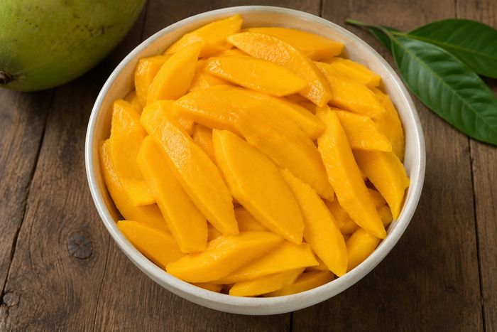 Sliced mango cheeks in a bowl, ready for freezing.